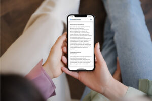 Zwei Personen halten zusammen Smartphone mit Website von OnlineDoctor